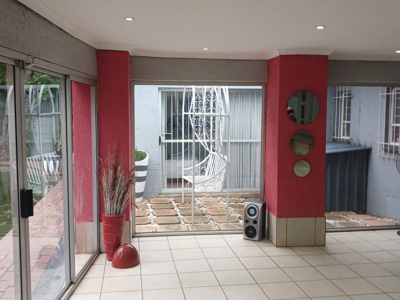 A spacious, enclosed patio area featuring tiled flooring, recessed lighting, and large sliding glass doors providing views of the garden and pool area.