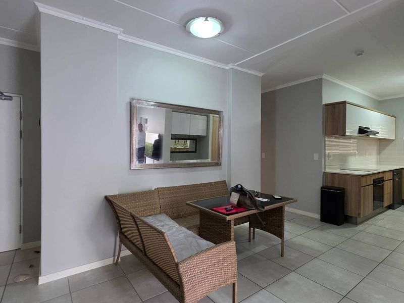 Open plan living and kitchen area featuring tiled flooring, modern wood-finish cabinetry, and integrated kitchen appliances in a neutral, well-maintained space.