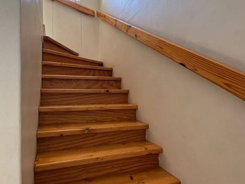 A simple timber staircase with a matching wooden handrail leading to the upper level of the townhouse.