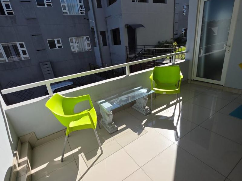A covered balcony featuring tiled flooring and a metal balustrade, providing an outdoor space accessible via a sliding glass door.