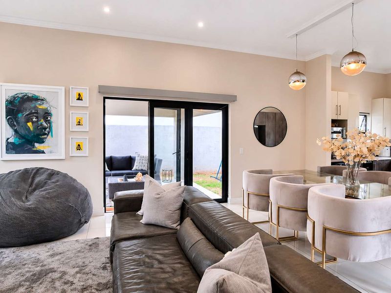 A modern open-plan living and dining area featuring tiled floors, recessed lighting, and seamless access to the rear patio through sliding glass doors.