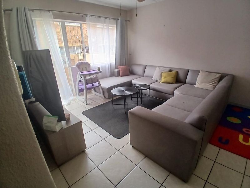 A functional living room featuring tiled flooring and a sliding glass door providing access to the exterior.