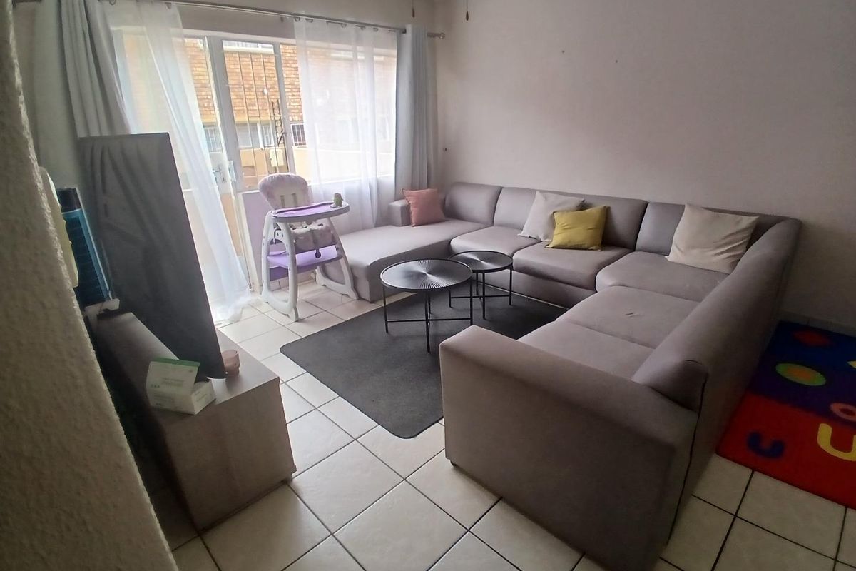 A functional living room featuring tiled flooring and a sliding glass door providing access to the exterior.