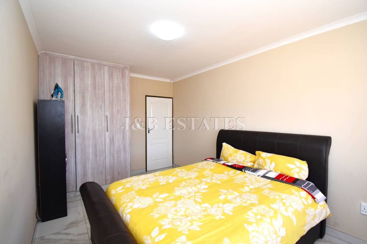 A well-maintained bedroom featuring built-in cupboards, tiled flooring, and neutral wall finishes, providing a clean and functional living space.