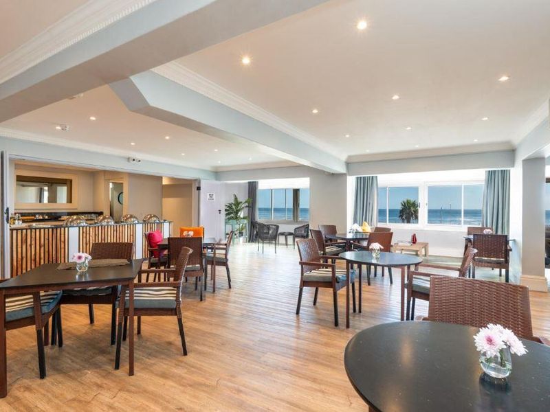 Spacious open-plan dining and living area featuring laminate flooring, recessed lighting, and large windows with scenic ocean views.