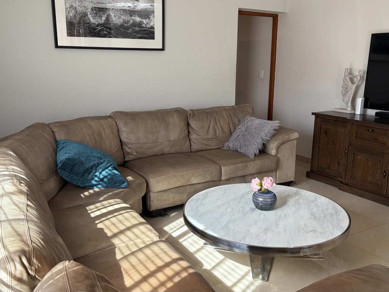 A comfortable living room featuring neutral tiled flooring and a doorway leading to an adjacent area.