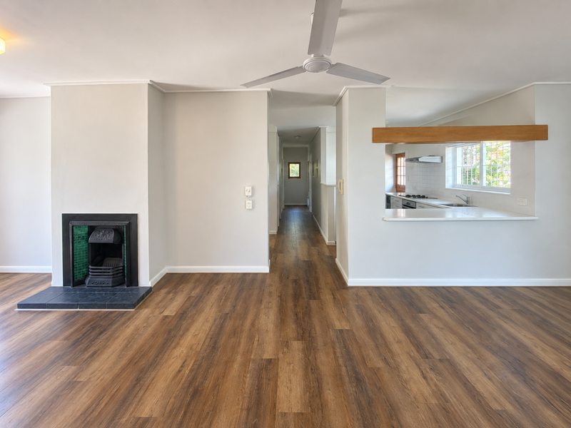 Spacious open-plan living area featuring a fireplace, modern laminate flooring, and a convenient kitchen pass-through with views into the kitchen space.