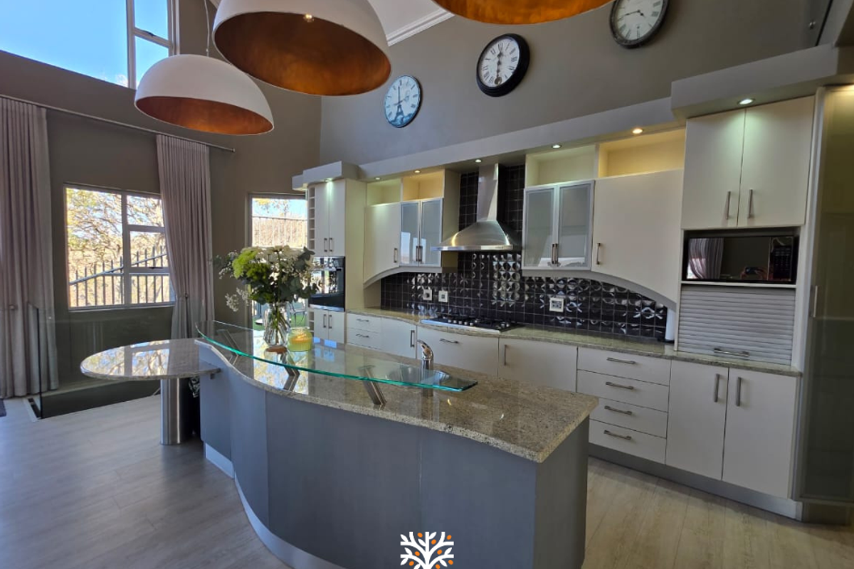 Modern kitchen featuring granite countertops, a curved breakfast bar, built-in appliances, and high ceilings with ample natural light.