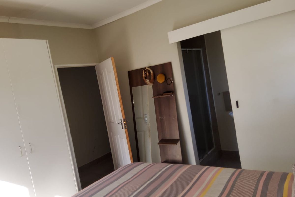 A bedroom featuring built-in cupboards and an en-suite bathroom access point with sliding door.
