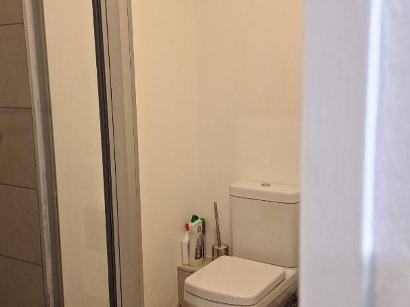A functional bathroom featuring a glass-enclosed shower and a standard toilet with tiled flooring.