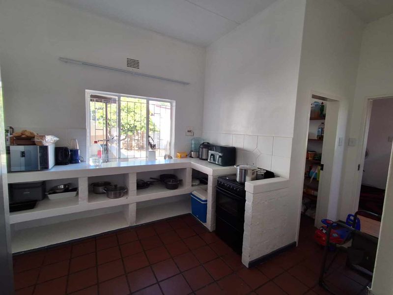 A functional kitchen featuring masonry cabinetry, tiled flooring, and a built-in pantry, offering a practical layout with potential for modern cosmetic updates.