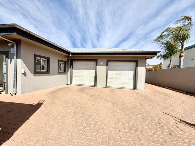 Exterior view of a double garage with a paved driveway and surrounding boundary wall.