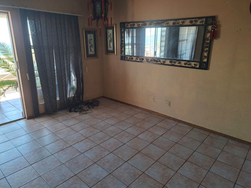 An empty living room featuring tiled flooring and a sliding glass door providing access to an outdoor area.