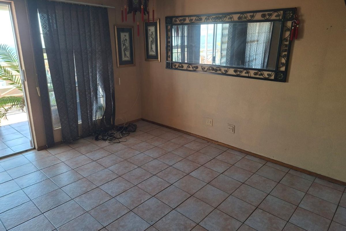 An empty living room featuring tiled flooring and a sliding glass door providing access to an outdoor area.