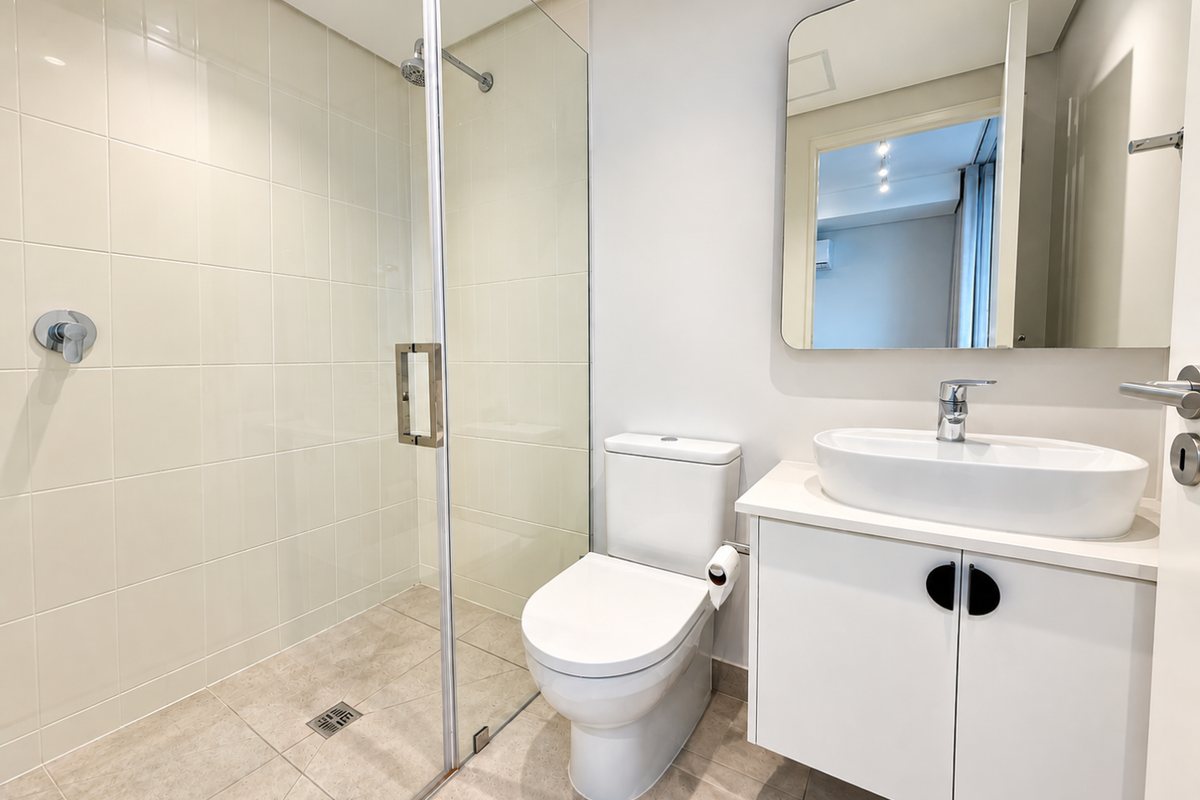 Modern bathroom featuring a glass-enclosed shower, a sleek vessel sink with vanity storage, and a wall-mounted mirror in a clean, contemporary finish.