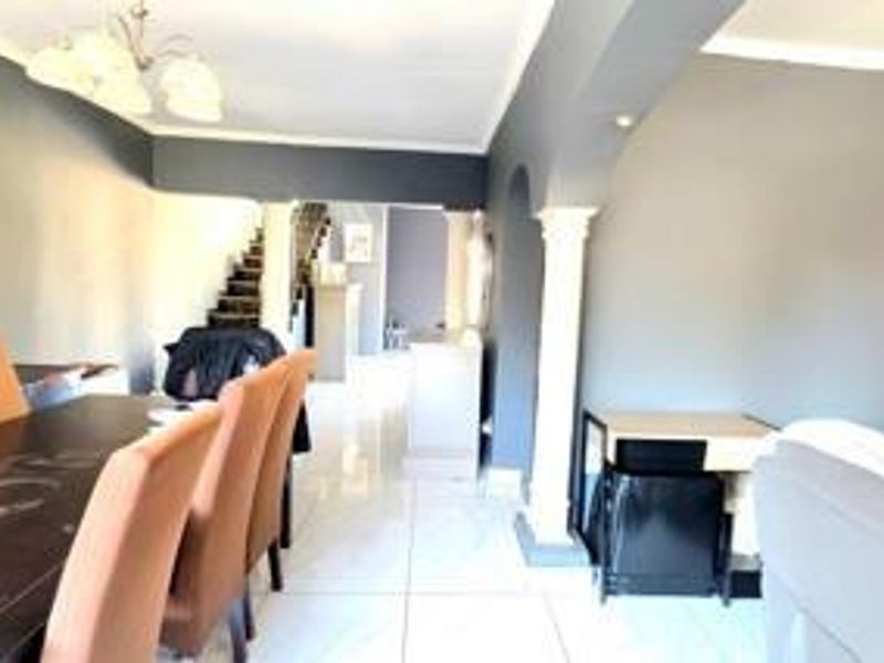 Open plan living and dining area featuring tiled flooring, decorative columns, and a staircase leading to the upper level.