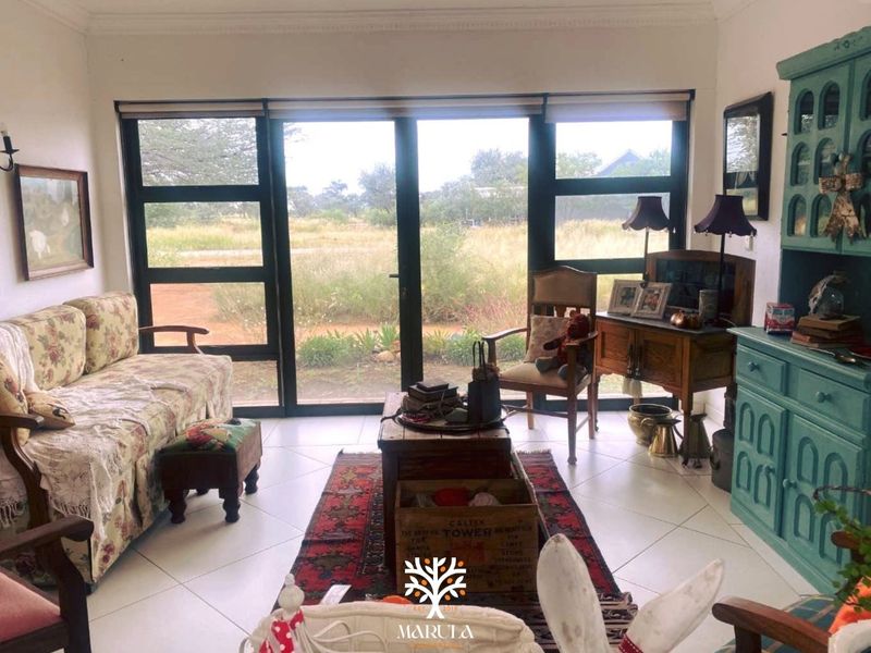 A bright living room featuring large glass sliding doors that provide natural light and views of the surrounding landscape, complemented by tiled flooring.