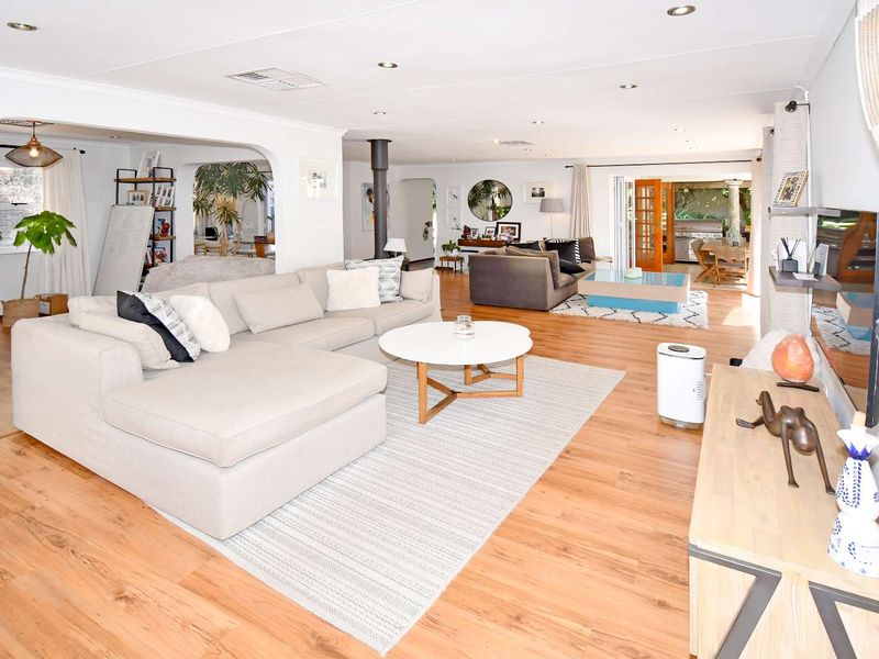 Spacious open-plan living area featuring warm wood flooring, a central fireplace, and seamless flow through bi-fold doors to the outdoor patio.