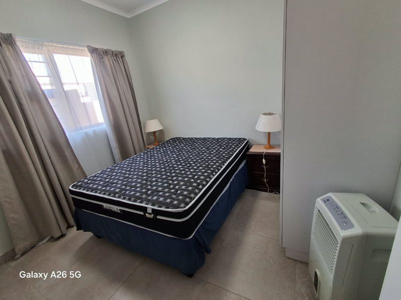 A functional bedroom featuring tiled flooring and a built-in wardrobe, providing a clean and neutral space ready for personalization.