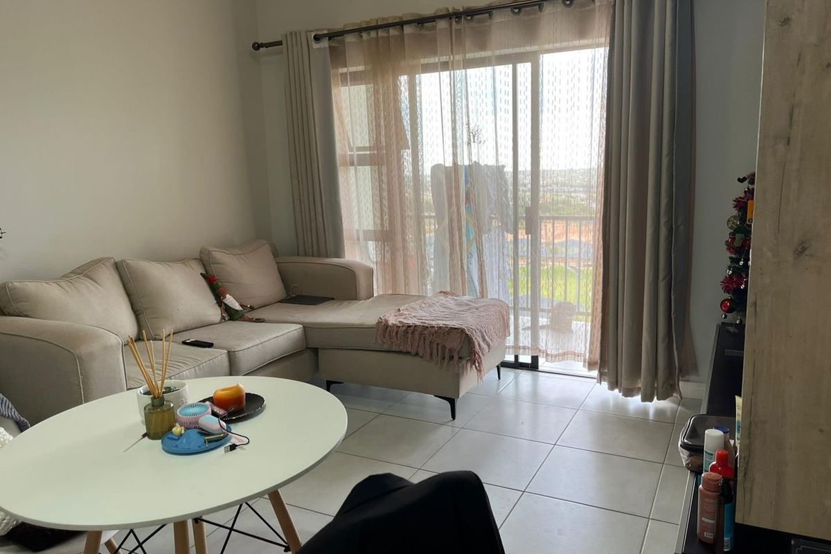 A living room featuring tiled flooring and a large sliding glass door that provides access to an outdoor balcony area.