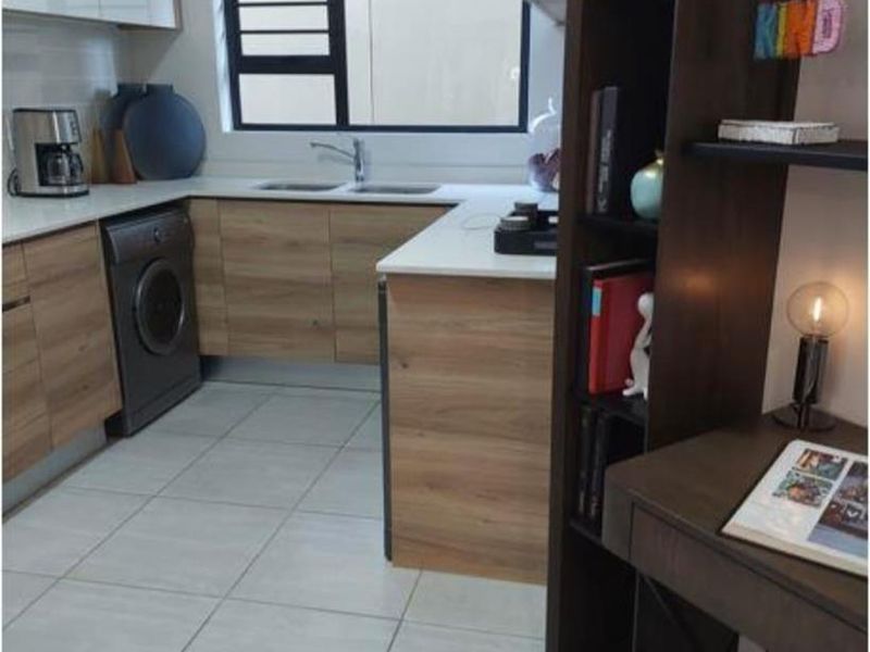 Modern kitchen featuring wood-look cabinetry, stone countertops, a double basin sink, and tiled flooring, with an integrated shelving unit for additional storage.