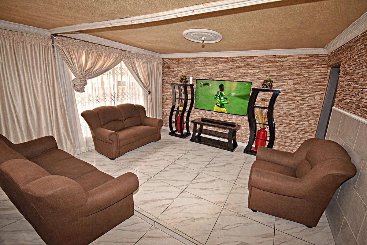 A living room featuring a stone veneer accent wall, ceramic tiled flooring, and decorative ceiling detailing.