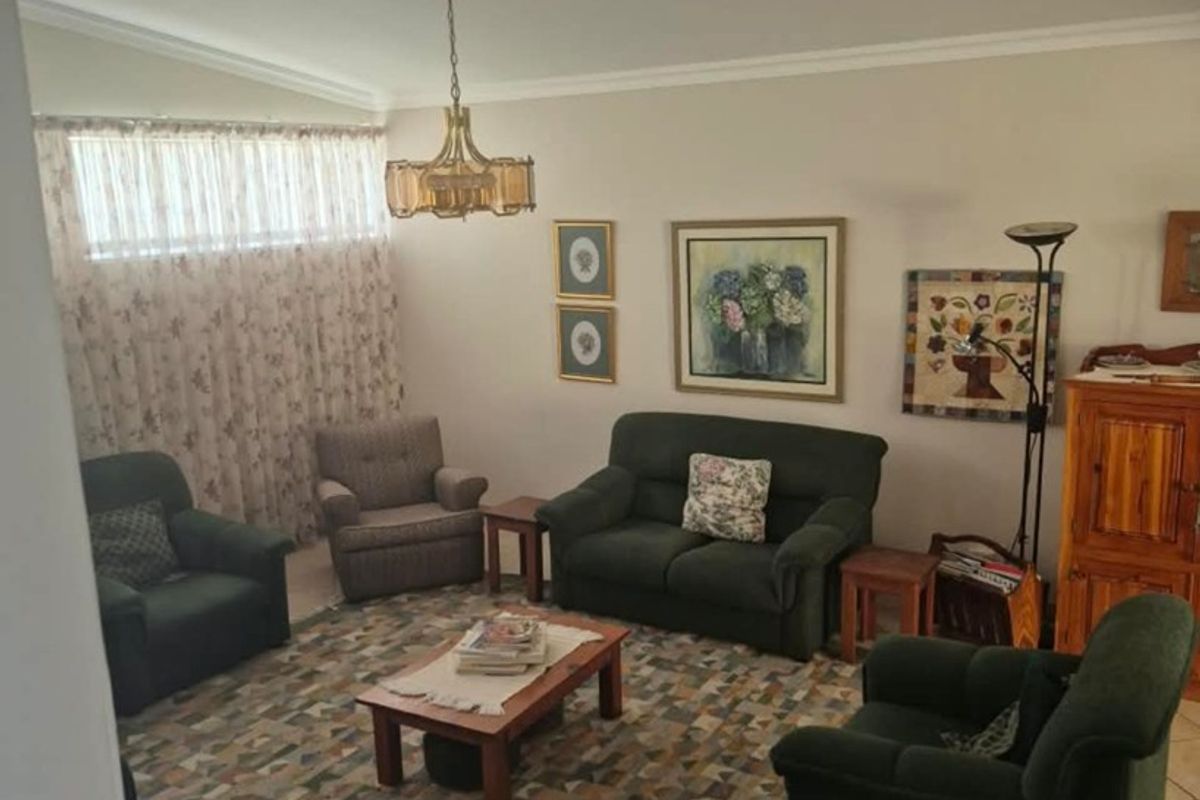 A spacious living room featuring tiled flooring, a high-level clerestory window, and decorative cove cornicing, offering a comfortable and functional living space.