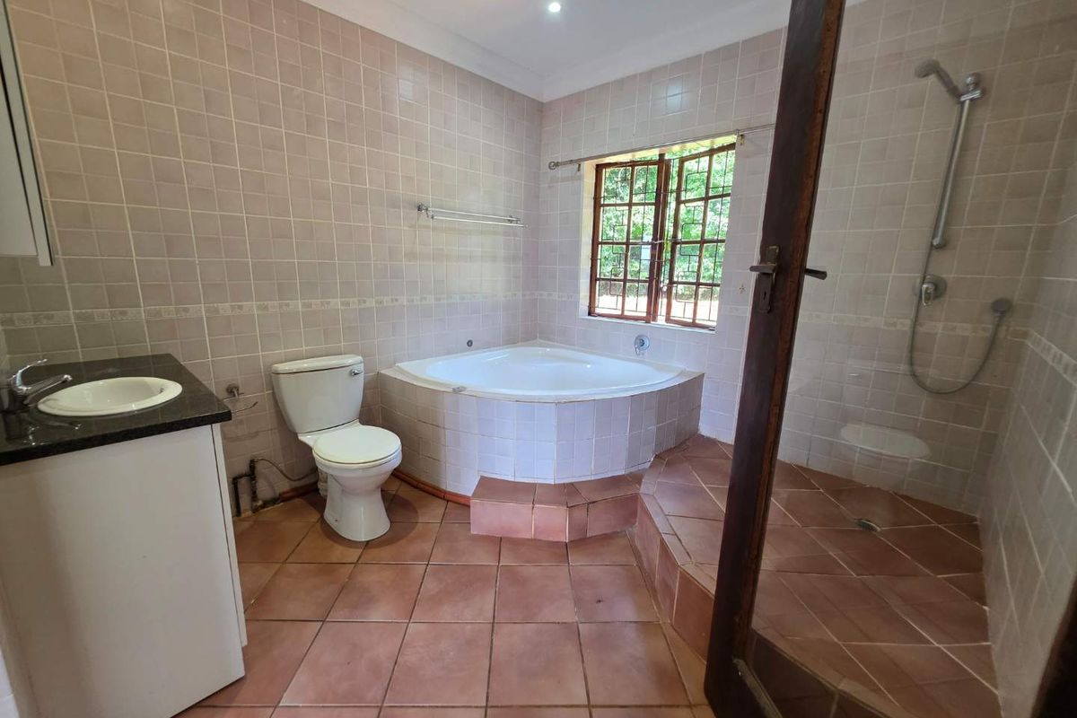 Spacious bathroom featuring a corner bathtub, separate walk-in shower, vanity cabinet, and neutral ceramic tiling throughout.