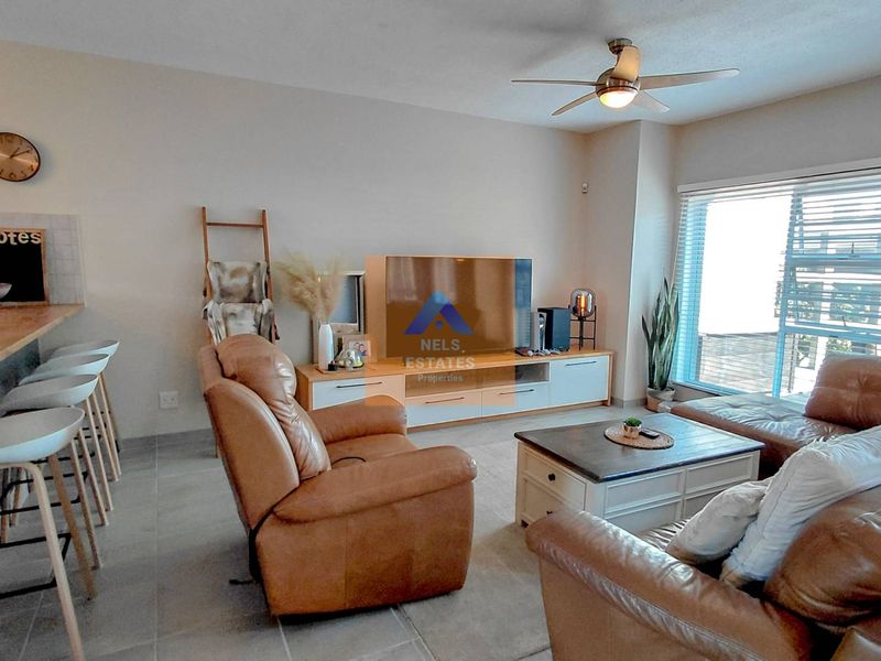 Open-plan living area featuring tiled flooring, a ceiling fan, and a breakfast bar counter, creating a functional and connected space.