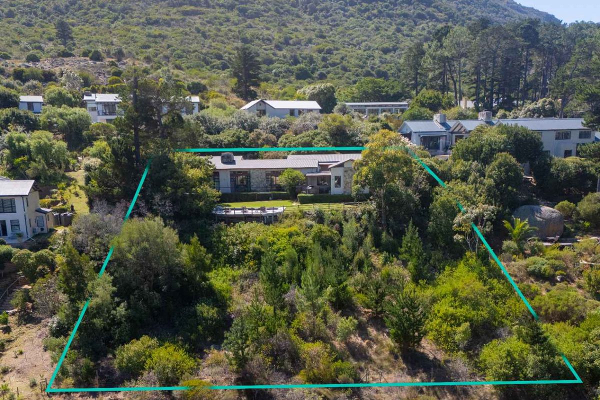 Aerial view of a residential property nestled in a lush, mountainous landscape, featuring a spacious garden and a large outdoor deck area.