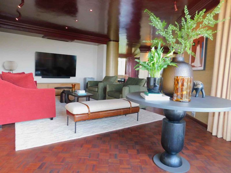 Spacious living room featuring rich parquet flooring, a high-gloss dark ceiling, and recessed lighting, creating a sophisticated and warm atmosphere.