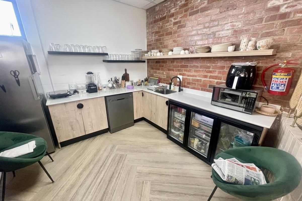 Modern kitchen featuring exposed brick walls, light wood-tone cabinetry, integrated dishwasher, glass-front under-counter refrigeration, and durable herringbone-patterned flooring.
