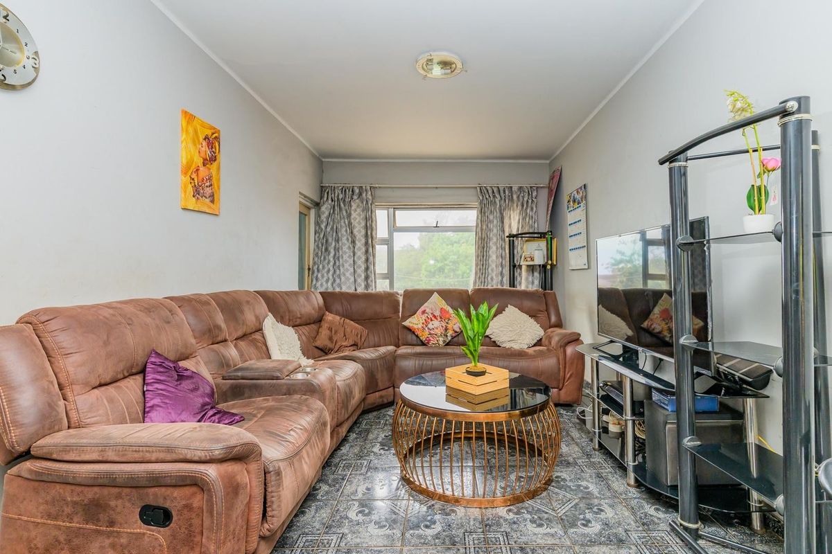 A living room featuring tiled flooring and a window, providing a functional space that could benefit from cosmetic updates to enhance its appeal.