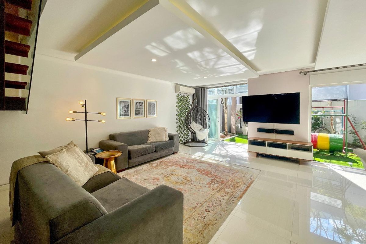 Spacious open-plan living area featuring polished tile flooring, a modern recessed ceiling design, and large glass sliding doors leading to the rear garden.