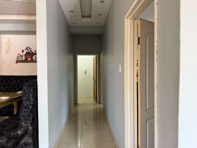 A functional hallway with tiled flooring and recessed ceiling lighting, connecting multiple interior spaces within the retail property.