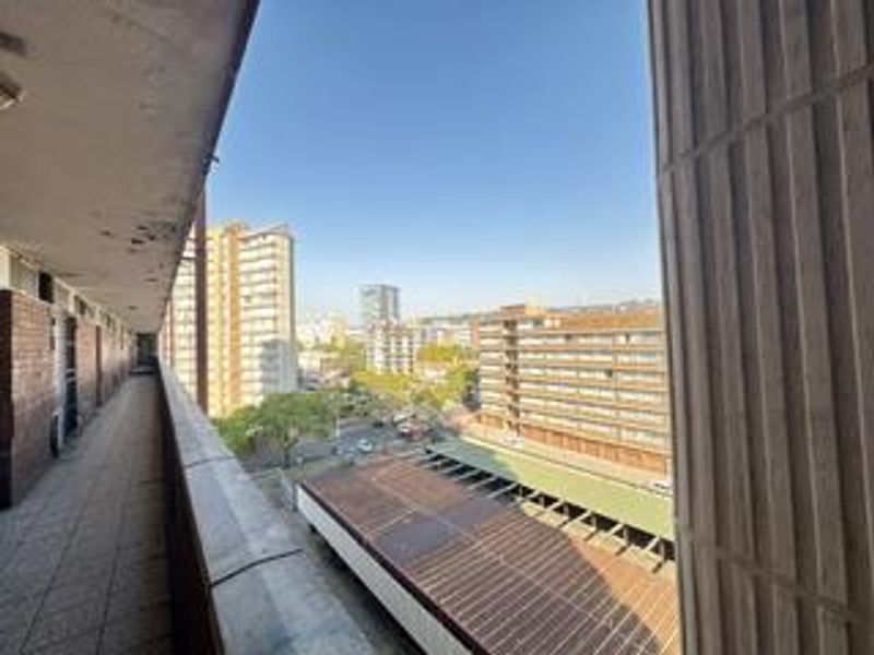 An open balcony area featuring tiled flooring and a concrete balustrade, offering an elevated urban view of the surrounding apartment buildings.