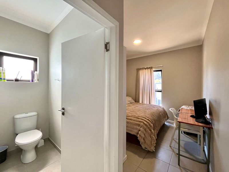 A bedroom featuring tiled flooring and recessed lighting, with an adjacent bathroom visible through the doorway.