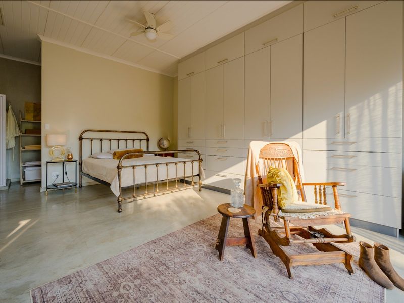 Spacious bedroom featuring extensive built-in cabinetry, polished concrete floors, a ceiling fan, and an integrated en-suite shower area.
