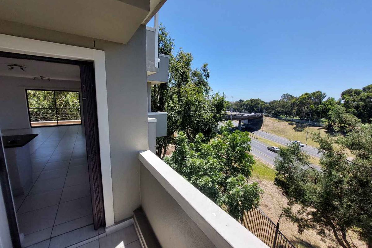 A balcony area with tiled flooring and a view overlooking the surrounding landscape and nearby road infrastructure.