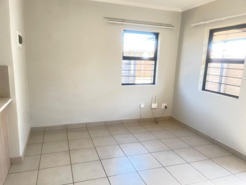 A clean, empty bedroom featuring neutral tiled flooring, large windows with security bars, and simple wall finishes, ready for personalization.