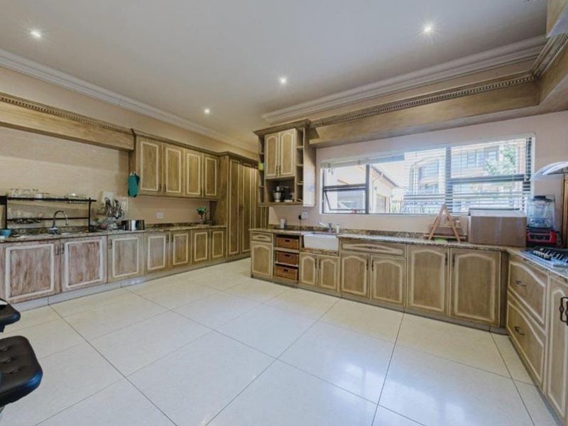 Spacious kitchen featuring extensive wooden cabinetry, granite countertops, a farmhouse sink, and tiled flooring with recessed lighting.