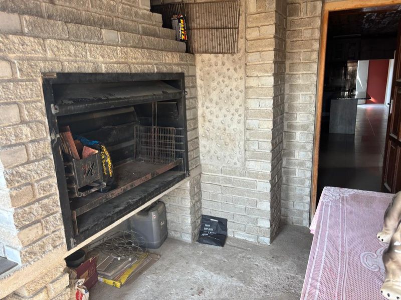 Covered patio area featuring a large built-in brick braai and concrete flooring, offering potential for an outdoor entertainment space.