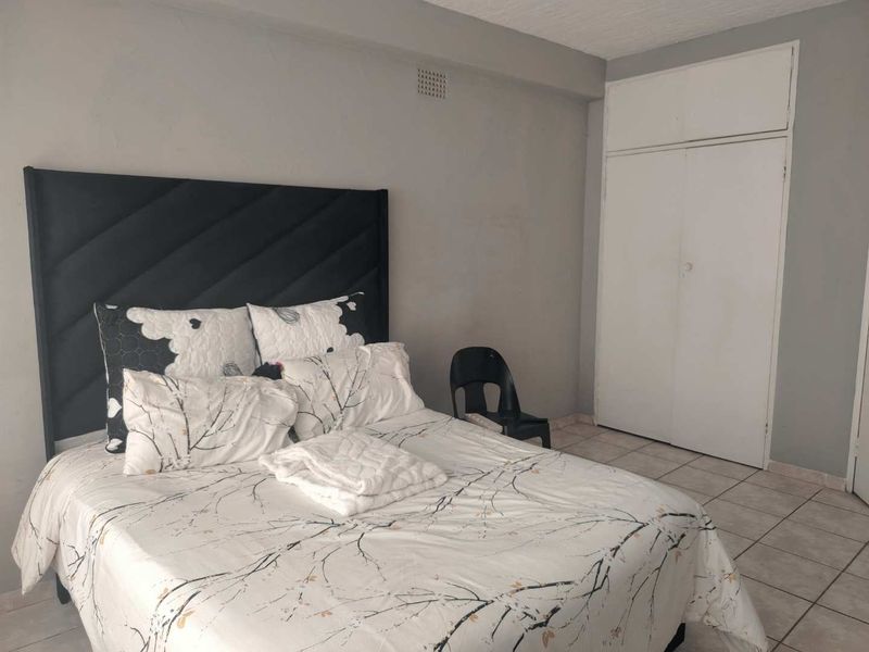 A bedroom featuring tiled flooring and a built-in wardrobe with overhead storage.