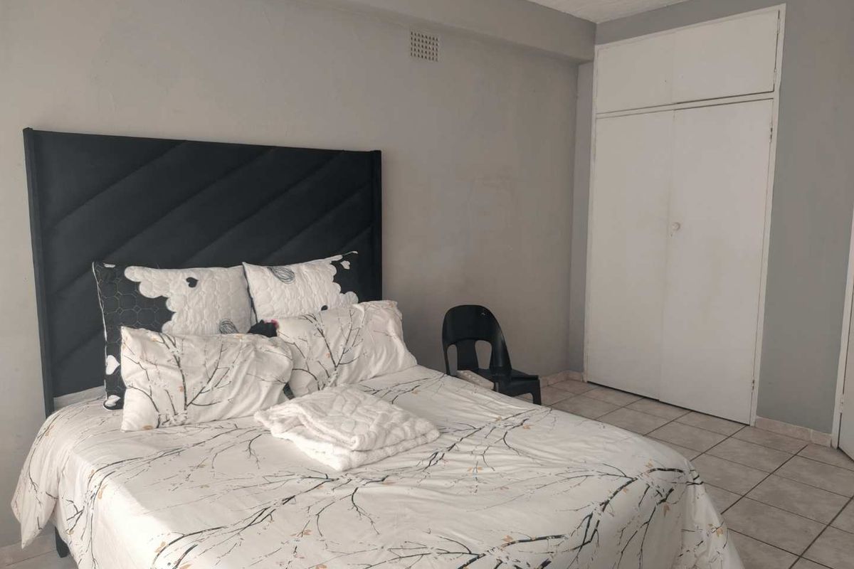 A bedroom featuring tiled flooring and a built-in wardrobe with overhead storage.