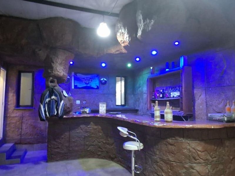 A themed bar area featuring custom rock-effect wall cladding, a built-in bar counter with shelving, and integrated recessed lighting.