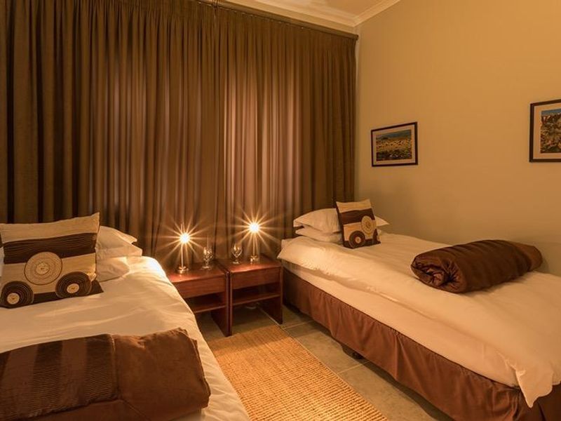 A bedroom featuring tiled flooring and full-length curtains, providing a functional and neutral space.