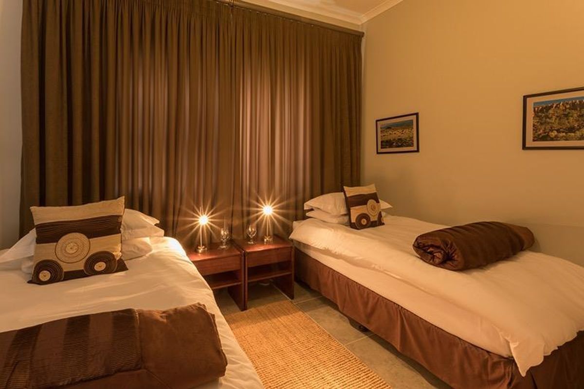 A bedroom featuring tiled flooring and full-length curtains, providing a functional and neutral space.