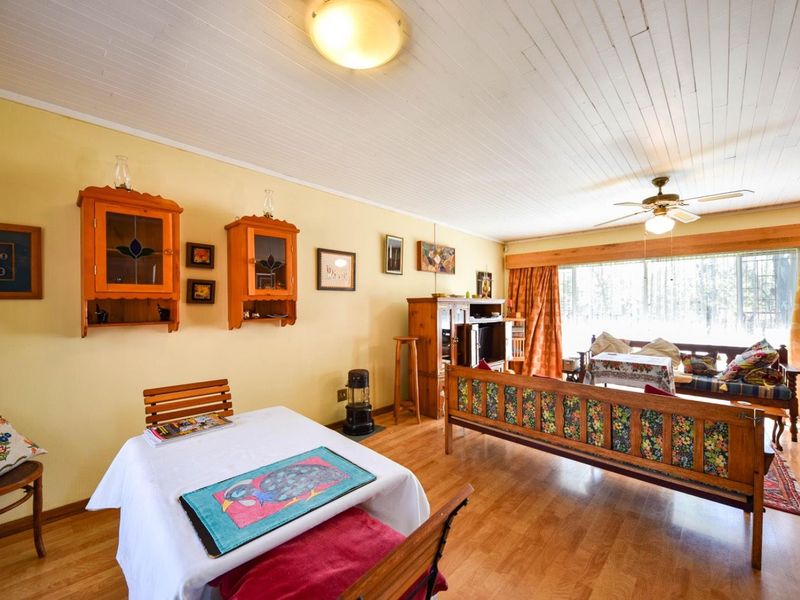 A living room featuring timber flooring, a ceiling fan, and tongue and groove ceiling panels with built-in wall cabinetry.