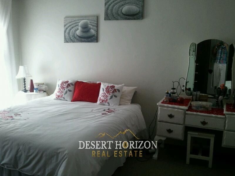 A standard bedroom featuring neutral walls and carpeted flooring, providing a functional space for rest.