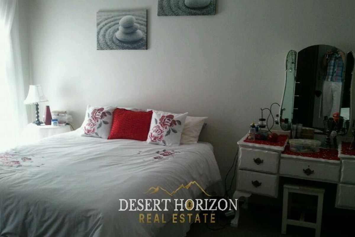 A standard bedroom featuring neutral walls and carpeted flooring, providing a functional space for rest.
